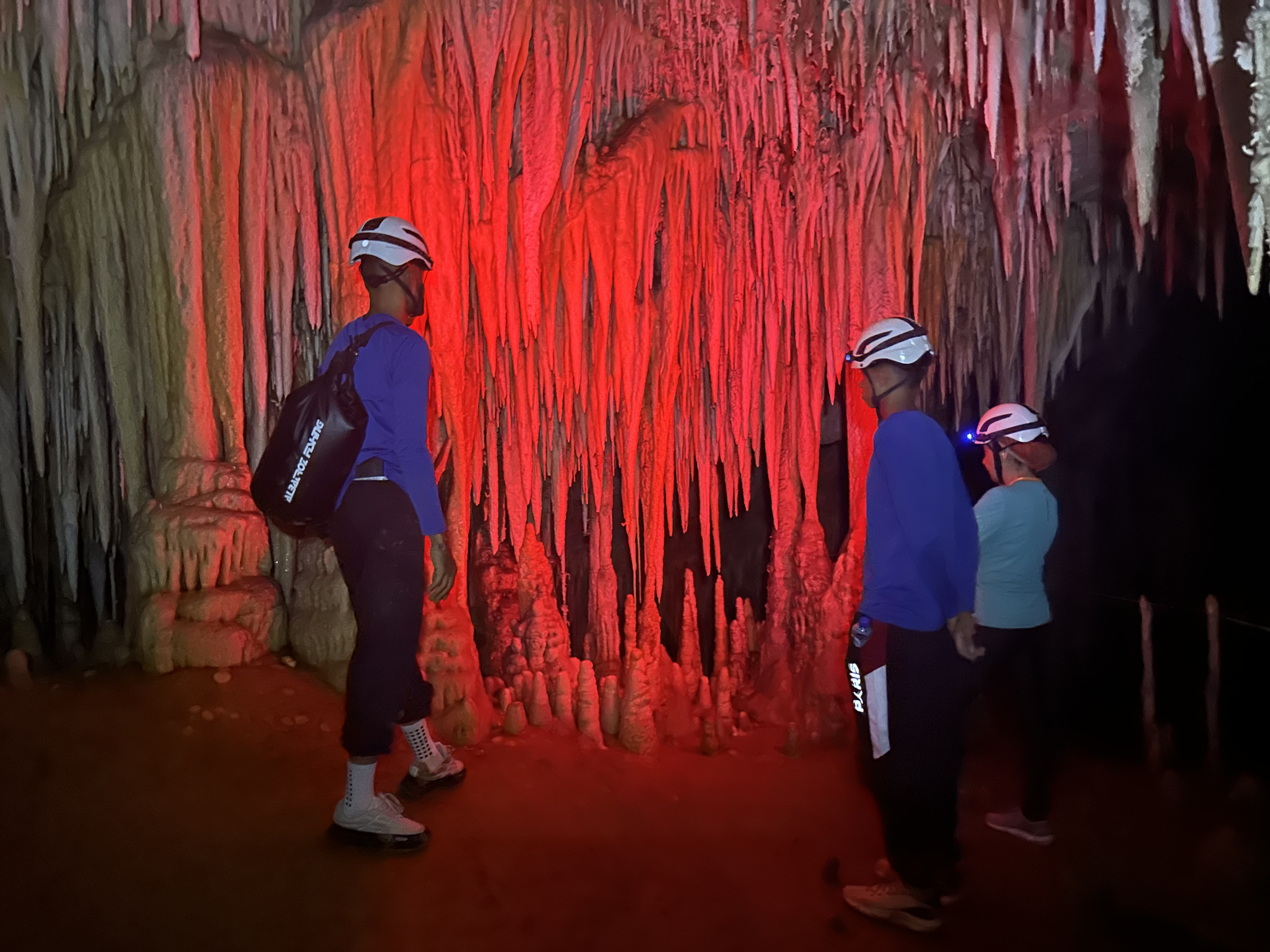 Exploradores diante de formações iluminadas em vermelho