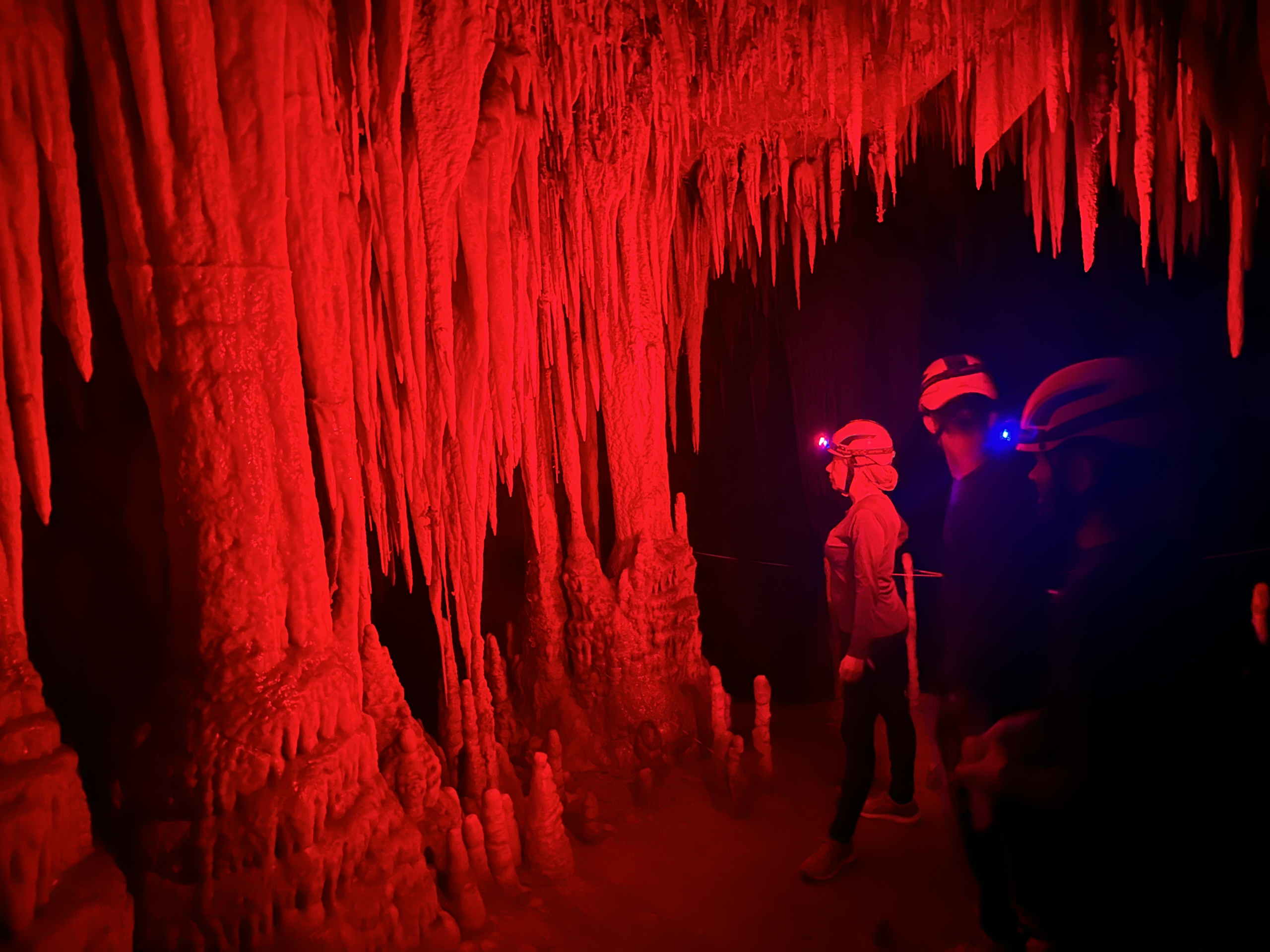 Caverna iluminada em vermelho com formações de estalactites